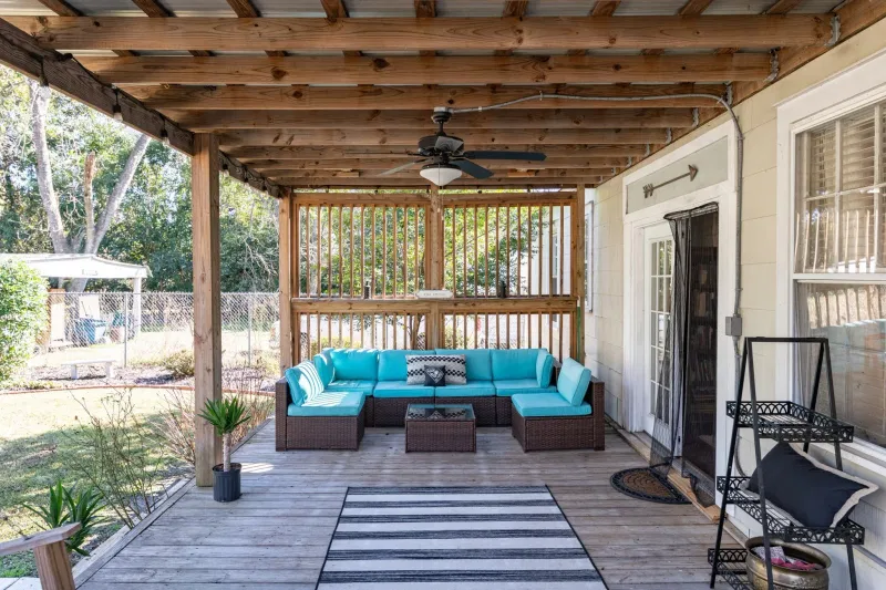 Covered porch with blue seating, ceiling fans, and a view into the garden.